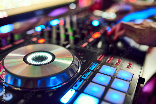 Dj mixes the track in the nightclub at party. In the background laser light show