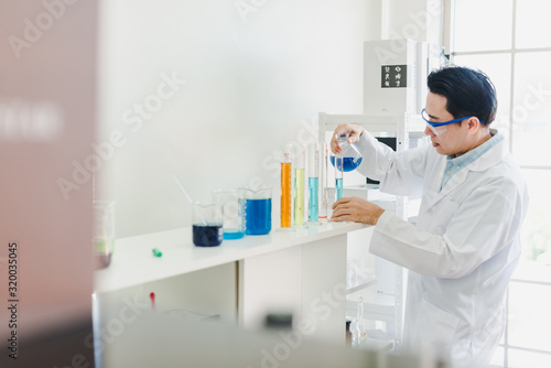 Asian scientists are preparing chemicals for testing and analysis in the laboratory. Scientists clear glasses and white shirts. Science and Chemistry Concept