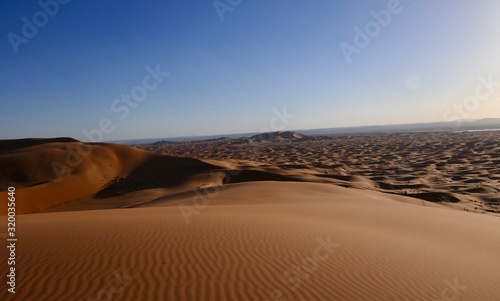 Fototapeta Naklejka Na Ścianę i Meble -  Sand dune with interesting shades and texture before desert landscape in Sahara during midday sun, Morocco, Africa