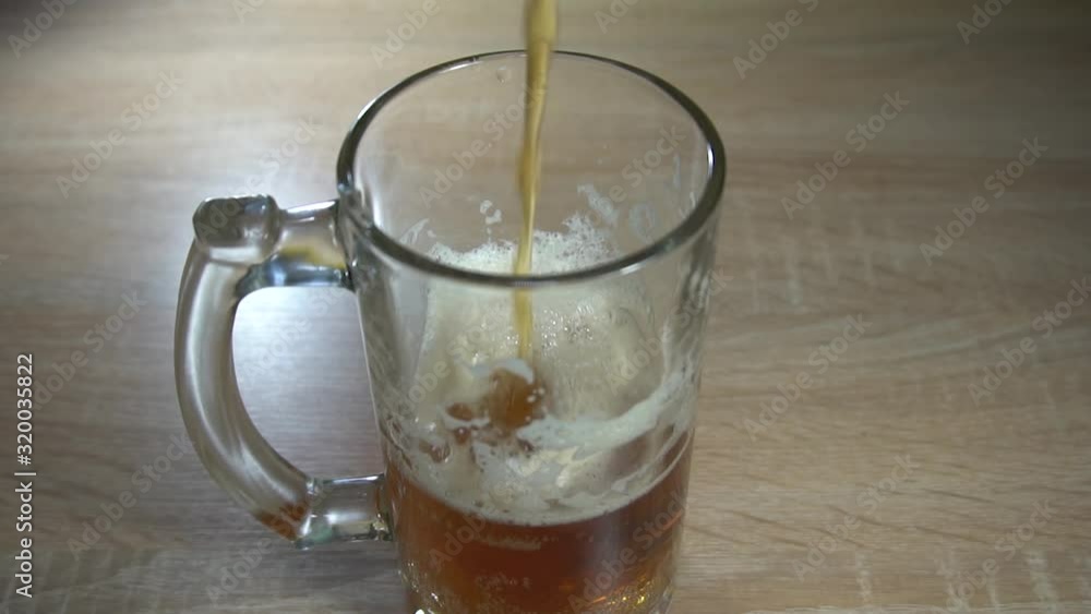 Fresh craft beer is slowly poured into a glass goblet with a handle. Slow motion video Fresh craft beer is slowly poured into a glass goblet with a handle. Slow motion video