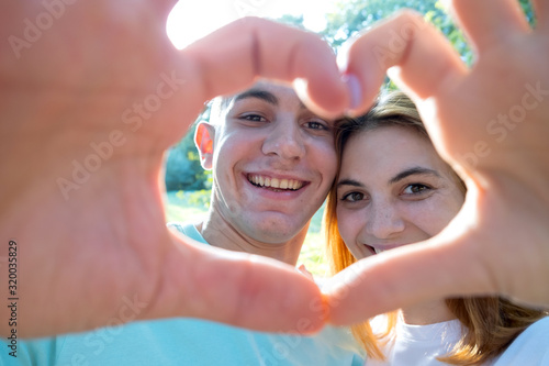Happy young couple taking selfie outdoors in warm sunny weather.