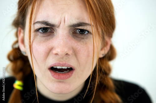 Close up portrait of angry redhead teenage girl. photo