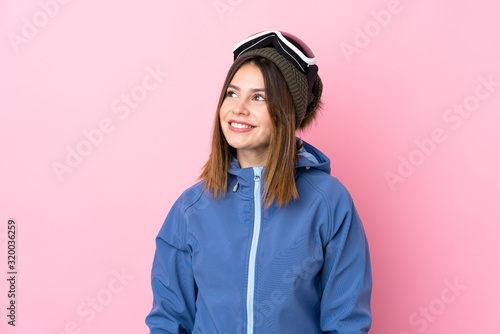 Young skier woman over isolated pink background laughing and looking up