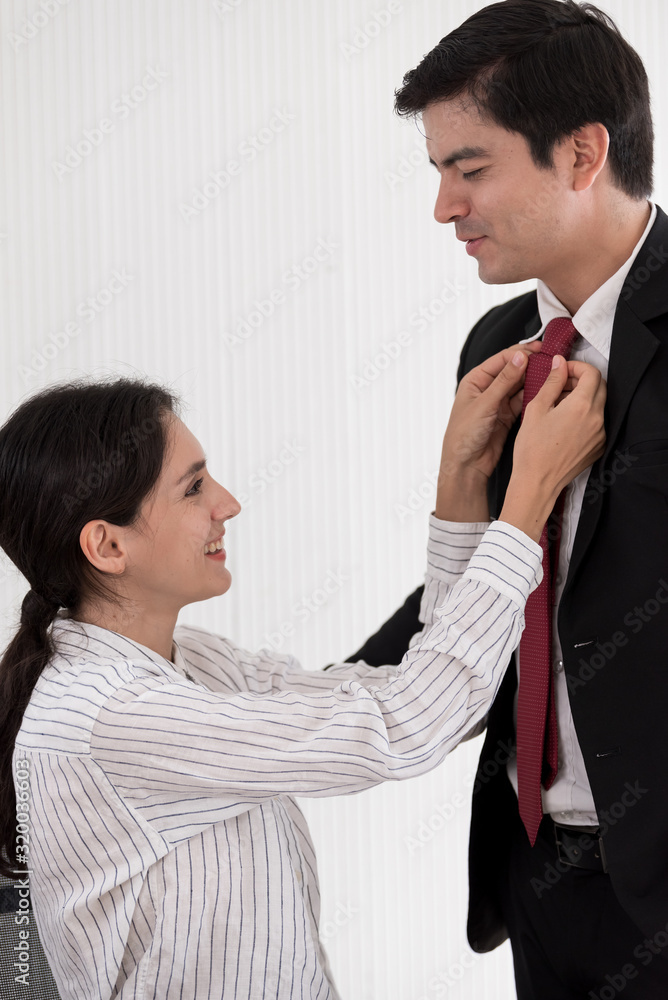 Wife tying red necktie to her husband in the office with smiling and happy. Wife tying red necktie to her husband in the office with smiling and happy.