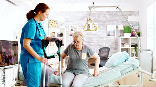 Social worker or nurse helping an elderly woman to walk with crutches photo