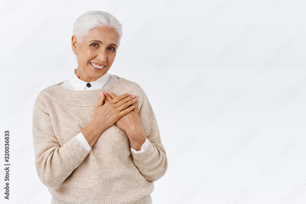 Lovely, touched senior wife receive charming gift for christmas or valentines day, press palms to heart feel flattered and delighted, smiling surprised with cute blush, stand happy white background Lovely, touched senior wife receive charming gift for christmas or valentines day, press palms to heart feel flattered and delighted, smiling surprised with cute blush, stand happy white background