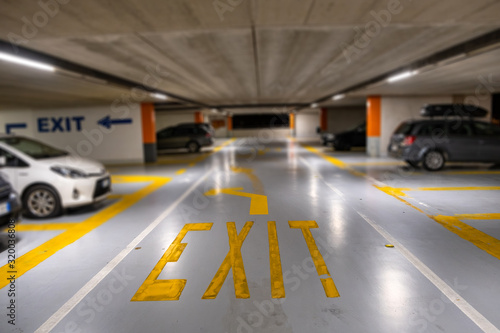 Yellow markings with blurred modern cars parked inside closed underground parking lot.