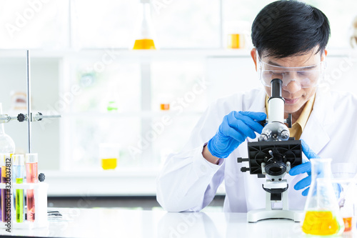 Senior Scientist looking through microscope in modern laboratory. Confident male health care professional in his working environment or researching about chemical in laboratory.