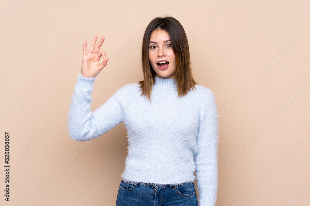Young woman over isolated background surprised and showing ok sign Young woman over isolated background surprised and showing ok sign