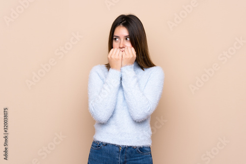 Young woman over isolated background nervous and scared putting hands to mouth