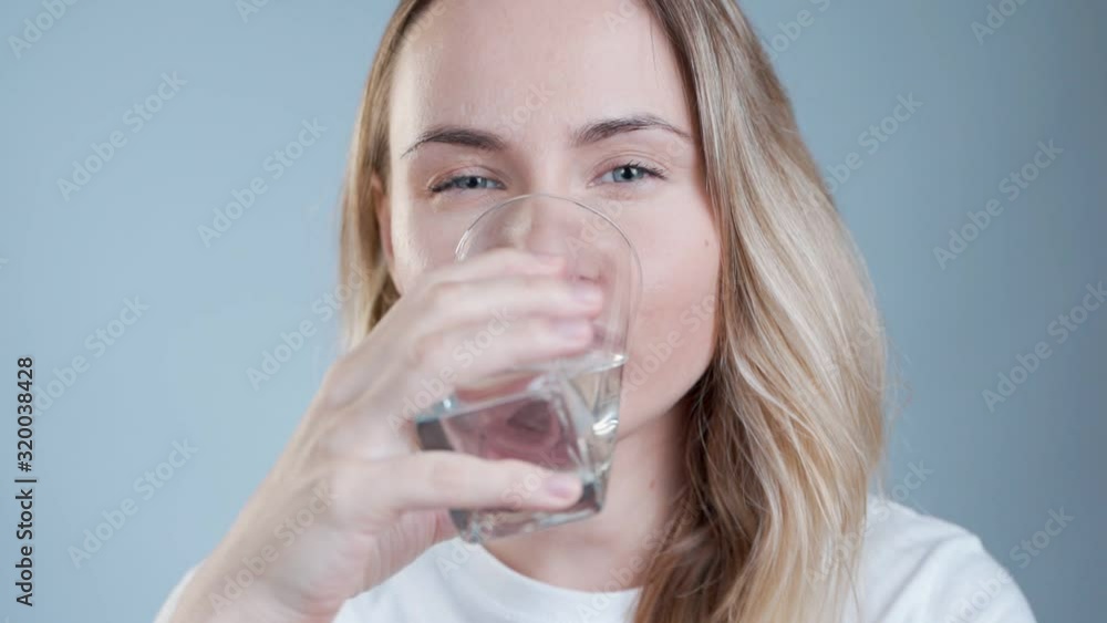 Woman drinking water. Smiling caucasian female model holding transparent glass in her hand. Closeup. Woman drinking water. Smiling caucasian female model holding transparent glass in her hand. Closeup.