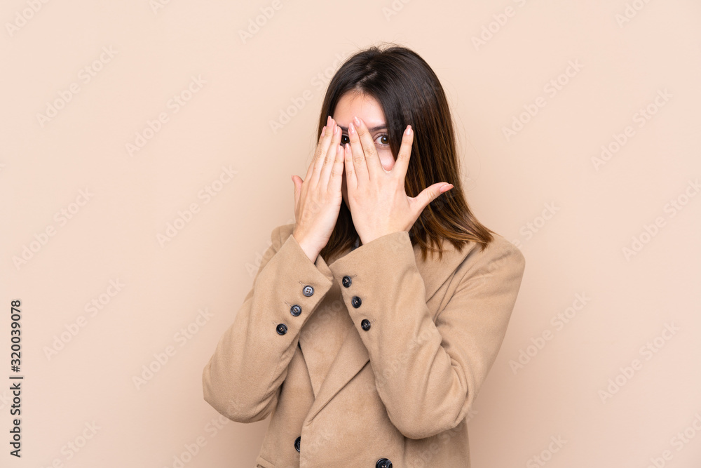 Young woman over isolated background covering eyes and looking through fingers Young woman over isolated background covering eyes and looking through fingers
