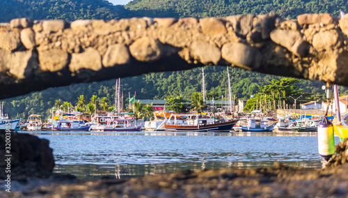 Multi-colored boats at the pier  view through the hole  the historical center of Paraty  Brazil. Popular tourist destination  travel theme