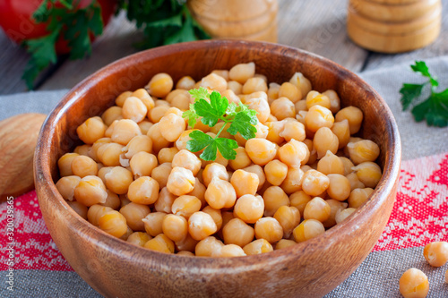 Boiled chickpeas in a wooden bowl on a wooden table, selective focus