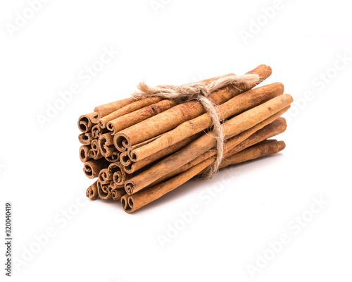 Studio shot pile of cinnamon sticks tied with jute string isolated on white