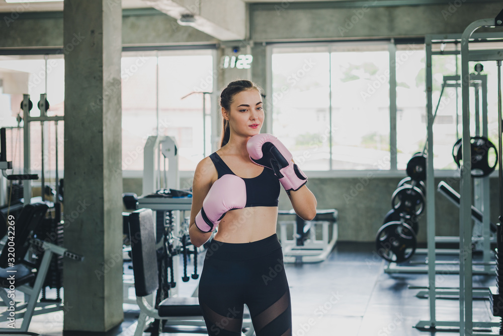 Fototapeta premium Beautiful girls exercise by boxing in the gym. She wears a pink boxing glove and wears exercise.