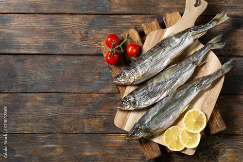 Canvas Print Smoked or dried smelt fish on a wooden Board on a brown wooden table