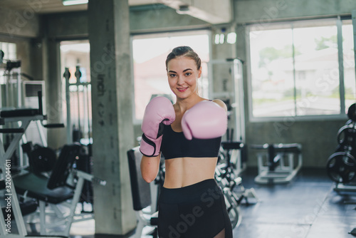 Beautiful girls exercise by boxing in the gym. She wears a pink boxing glove and wears exercise.