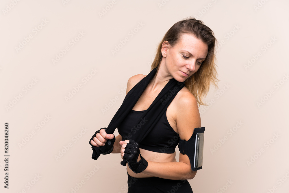 Blonde sport woman over isolated background with sport towel Blonde sport woman over isolated background with sport towel