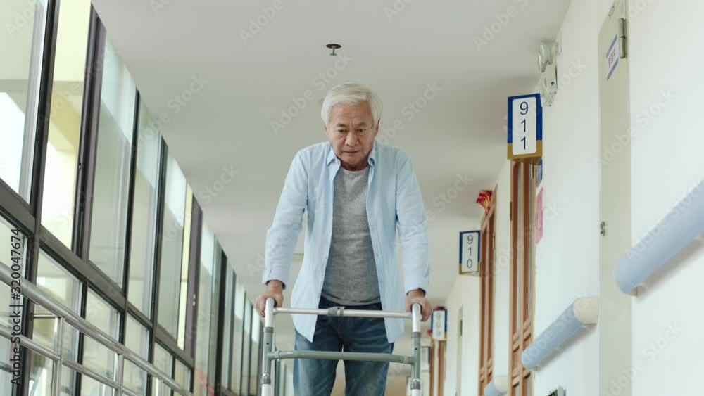 asian old man walking using a walker in hallway of nursing home asian old man walking using a walker in hallway of nursing home