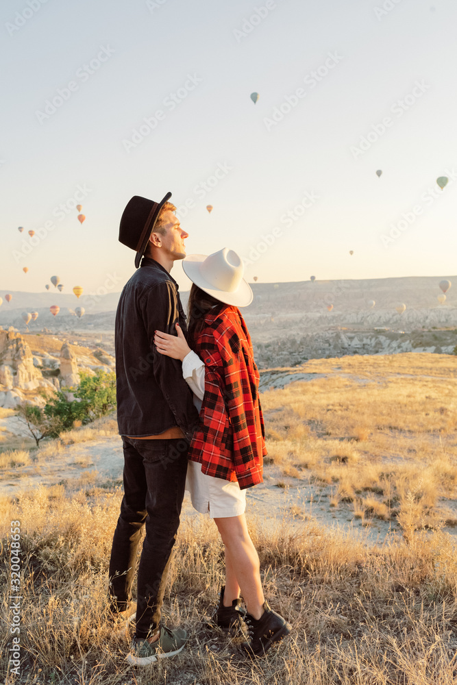 Wedding travel. Honeymoon trip. Couple in love among balloons. A guy proposes to a girl. Couple in love in Cappadocia. Couple in Turkey. Man and woman traveling. Flying on balloons. Tourists