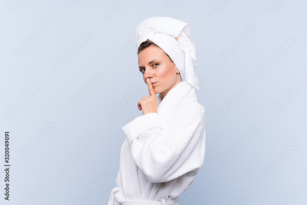 Woman in bathrobe over isolated blue background doing silence gesture Woman in bathrobe over isolated blue background doing silence gesture