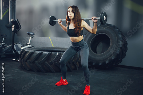 Beautiful girl in the gym. Girl with a sports body.Woman with a barbell photo