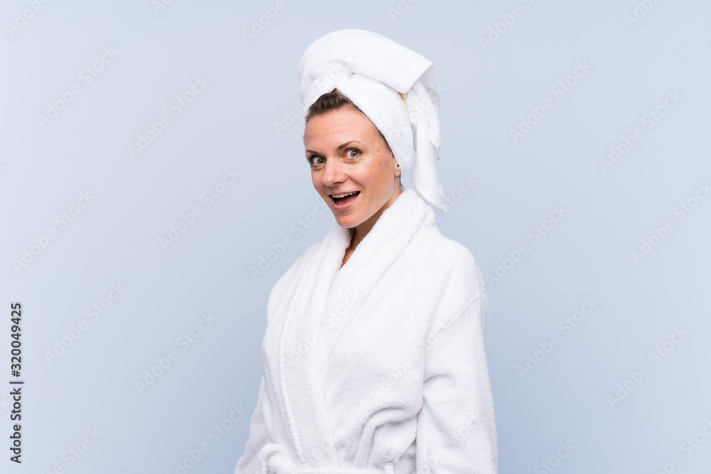 Woman in bathrobe over isolated blue background with surprise facial expression Woman in bathrobe over isolated blue background with surprise facial expression