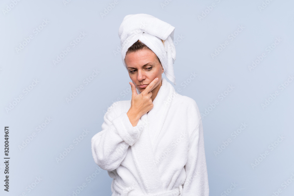 Woman in bathrobe over isolated blue background thinking an idea Woman in bathrobe over isolated blue background thinking an idea