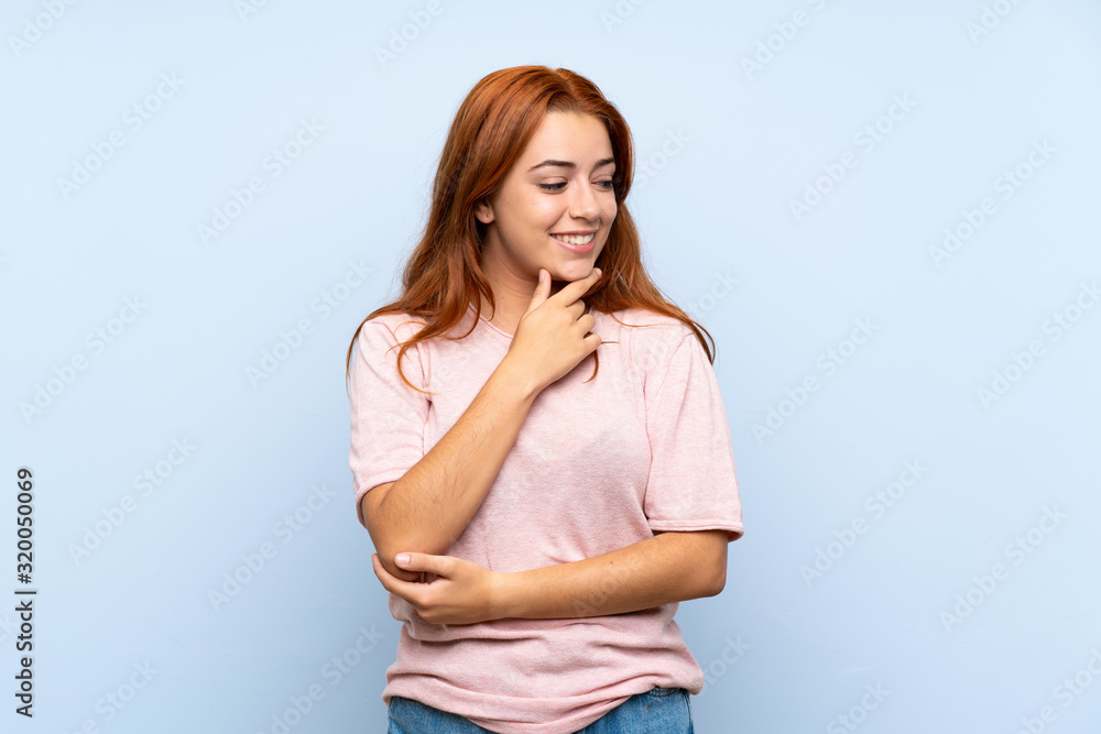 Teenager redhead girl over isolated blue background looking to the side Teenager redhead girl over isolated blue background looking to the side