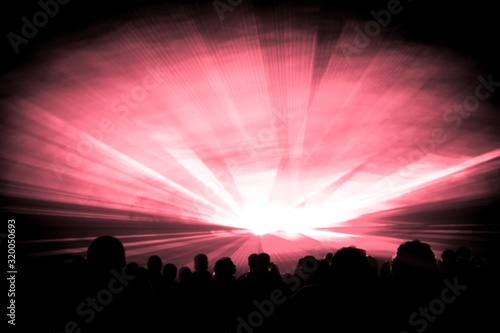 Red laser show nightlife club stage with party people crowd. Luxury entertainment with audience silhouettes in nightclub event  festival or New Years Eve. Beams and rays shining colorful lights