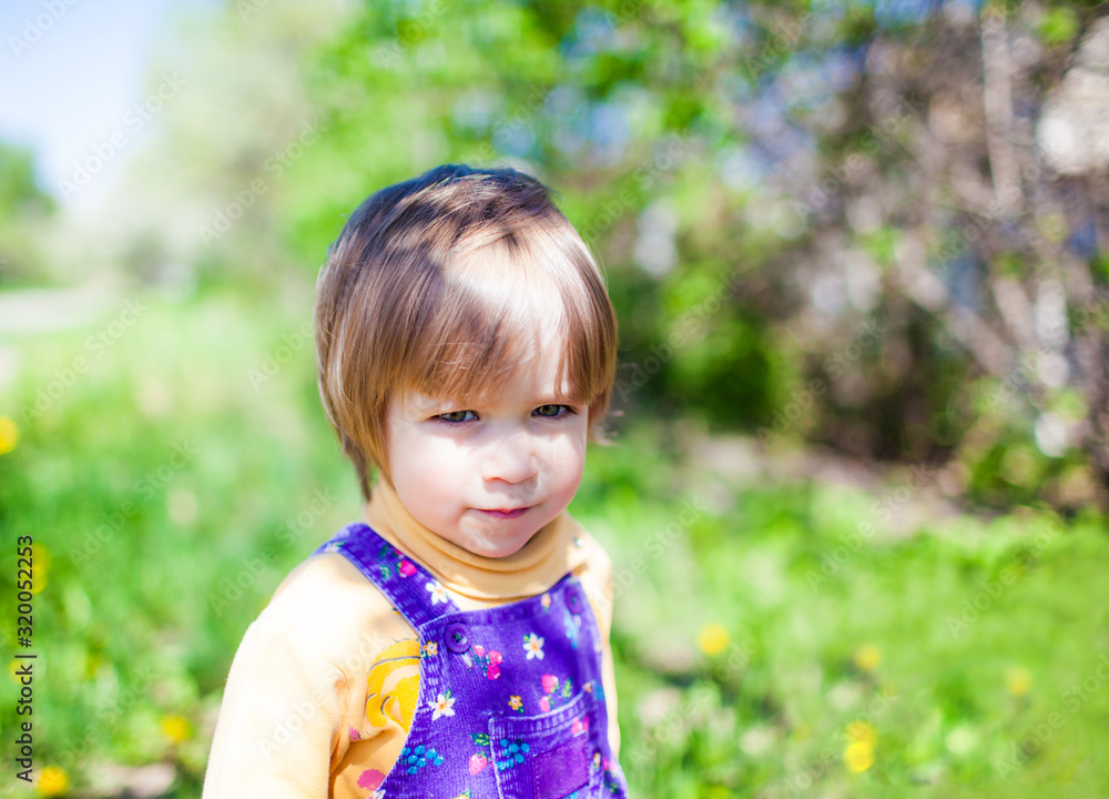 Portrait of small child in jumpsuit outdoors on green nature on summer sunny clear day. Happy childhood concept Portrait of small child in jumpsuit outdoors on green nature on summer sunny clear day. Happy childhood concept
