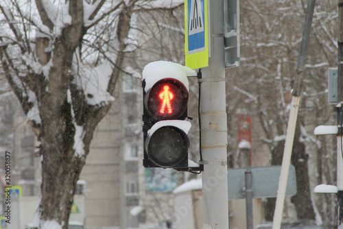 Traffic light for pedestrians with a red light in the shape of a human figure on a pillar in the city