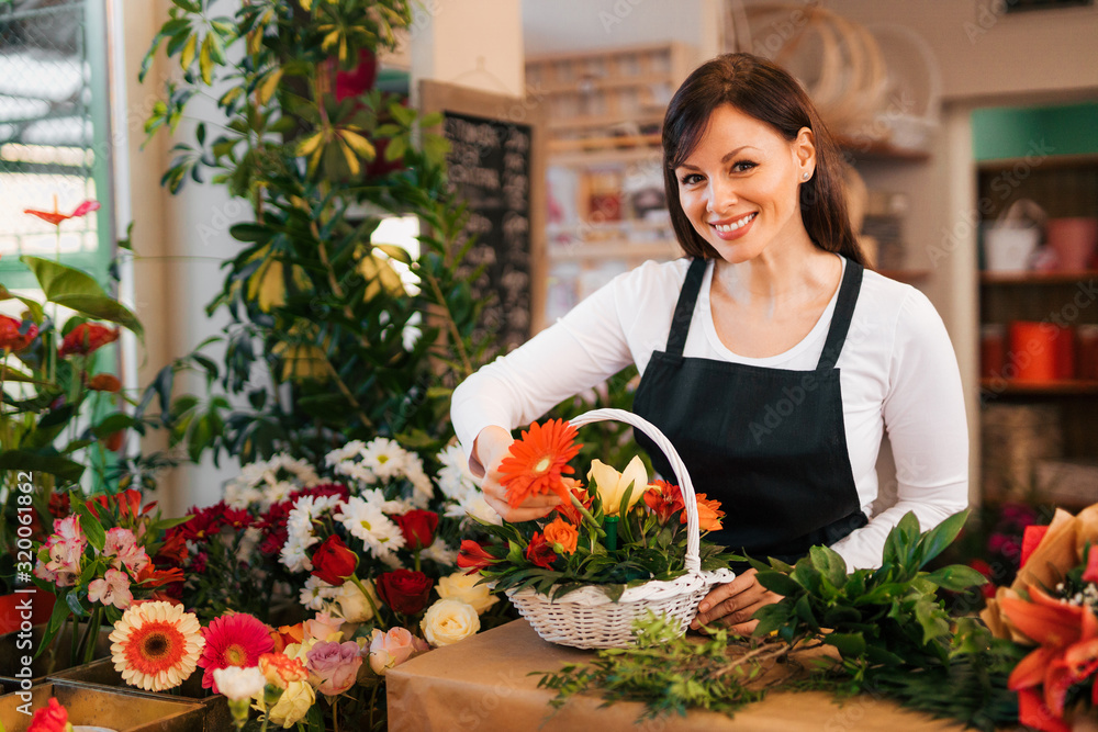Portrait of a florist making flower arrangement out of variety of fresh flowers in the basket.