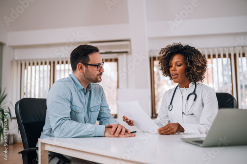 Canvas Print Doctor talking to a patient at medical clinic.