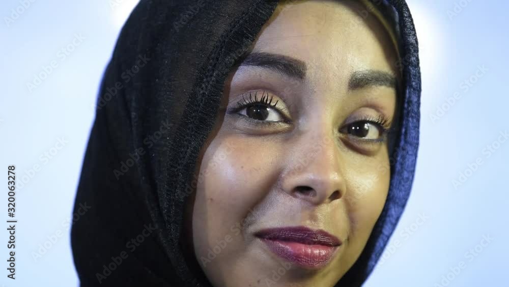 Close portrait of young Muslim woman's face looking at camera in hijab, happy expression Close portrait of young Muslim woman's face looking at camera in hijab, happy expression