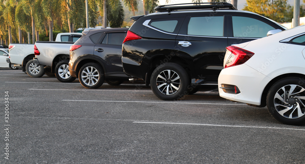 Closeup of rear, back side of white car with other cars parking in outdoor parking area in twilight evening. Closeup of rear, back side of white car with other cars parking in outdoor parking area in twilight evening.
