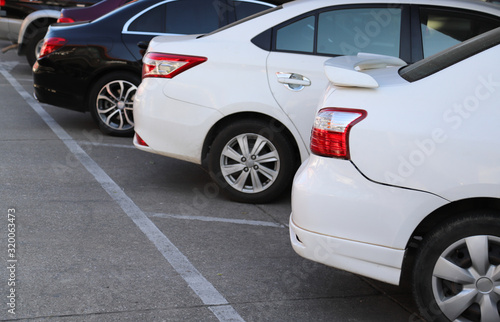 Closeup of rear side of white car with other cars parking in parking area.