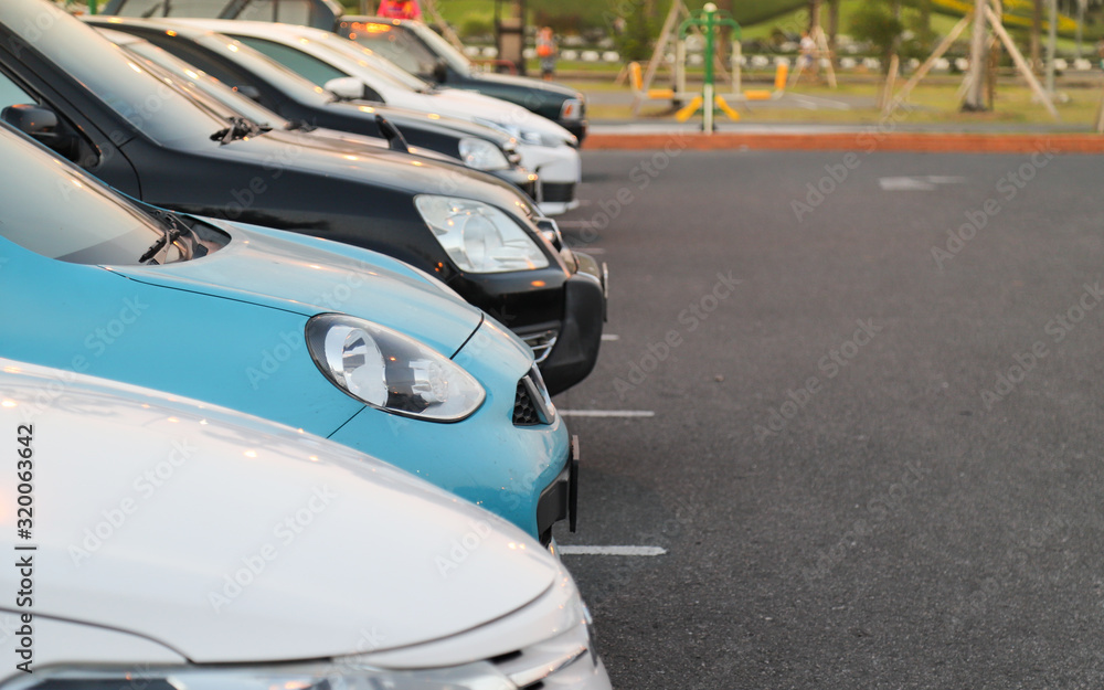Closeup of front side of sky blue car and other cars parking in outdoor parking lot with natural background in twilight evening. 