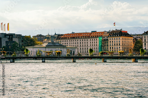 Pont de la Machine Bridge over Geneva Lake with a view on Quai des Bergues embankment, Geneva city center, Switzerland in summer. People on the background