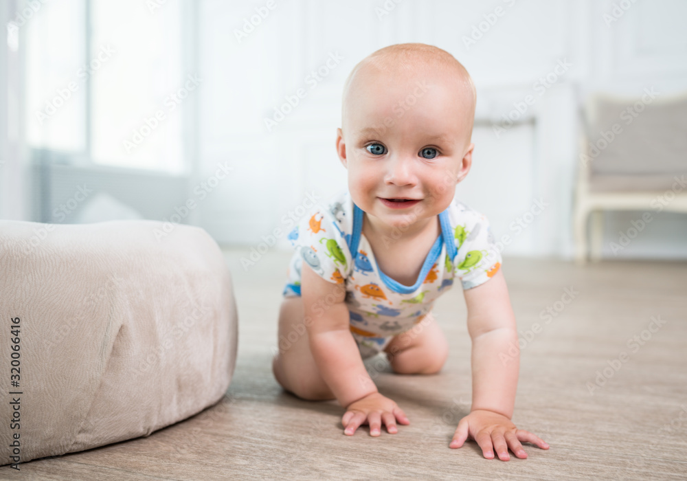 Portrait of a little happy baby crawling on the floor. The concept of a healthy developed child. Preparing for the first steps of the baby Portrait of a little happy baby crawling on the floor. The concept of a healthy developed child. Preparing for the first steps of the baby