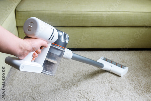 Wireless vacuum cleaner, stick hoover used on carpet in room at home