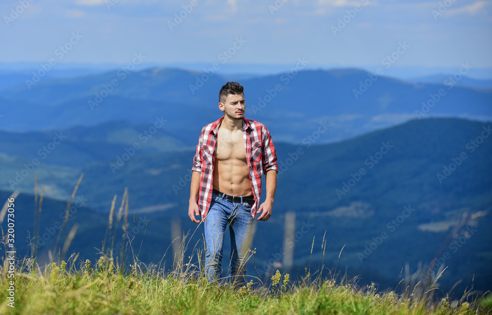 Muscular tourist walk mountain hill. Hiker muscular torso reach mountain peak. Hiking concept. Man stand top mountain landscape background. Athlete guy relax mountains. Beautiful environment