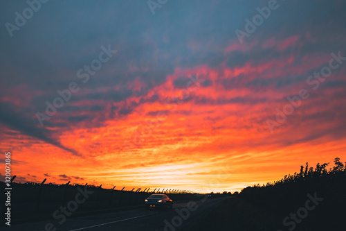 Fototapeta Naklejka Na Ścianę i Meble -  A Car Driving Towards The Sunset