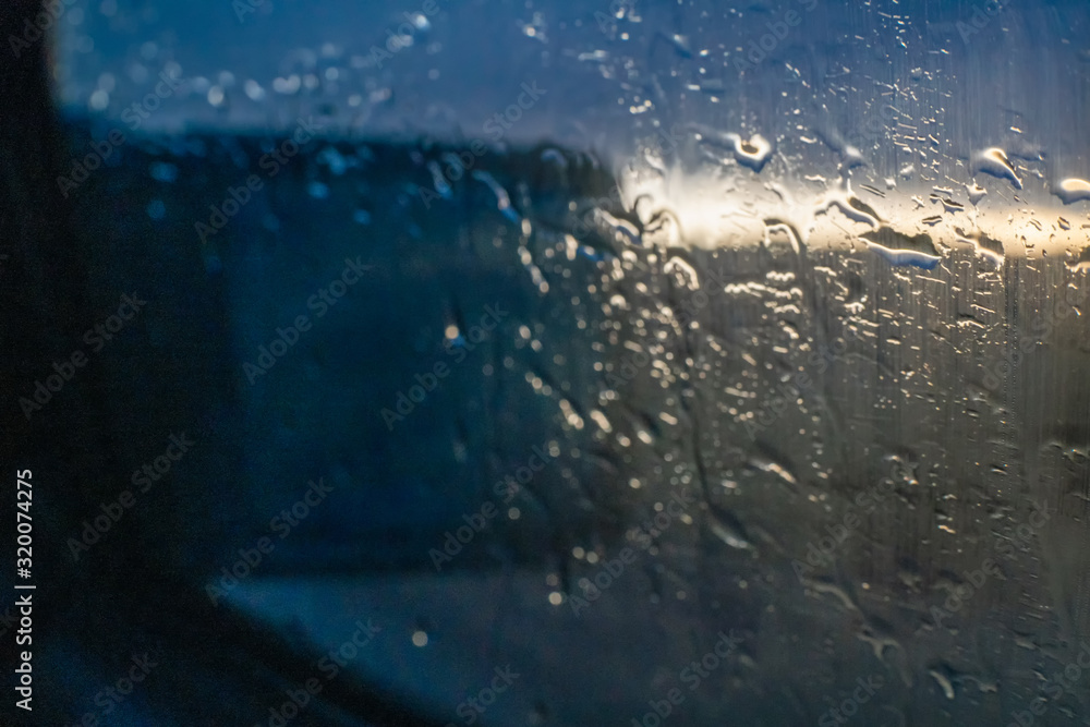 Water drops fall on the passenger window and mirror of the car on the background of the sunset Water drops fall on the passenger window and mirror of the car on the background of the sunset
