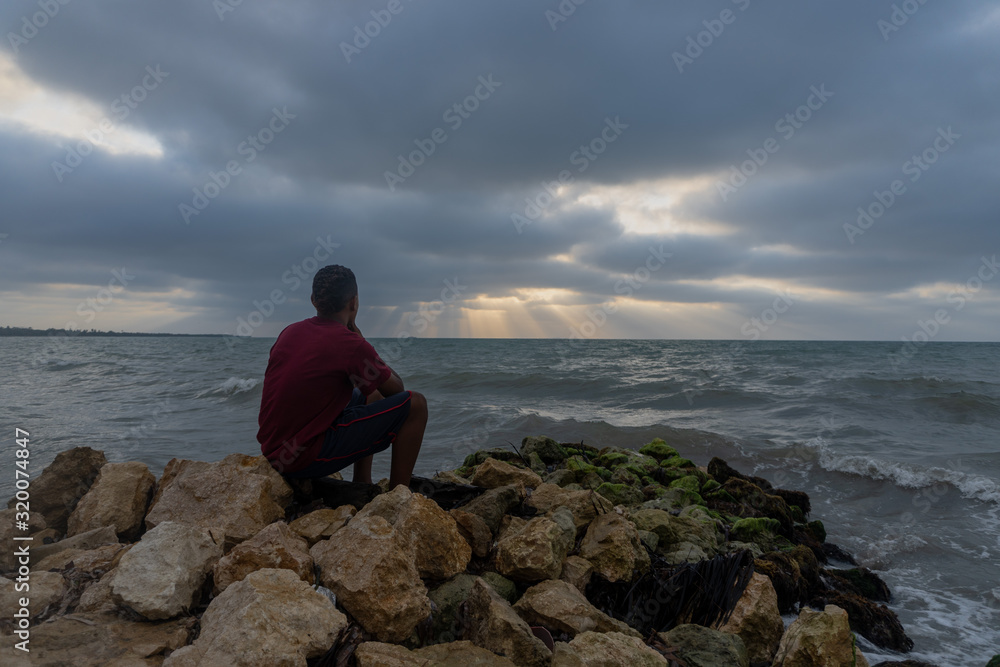 persona viendo rayos de luz a lo lejos del mar persona viendo rayos de luz a lo lejos del mar