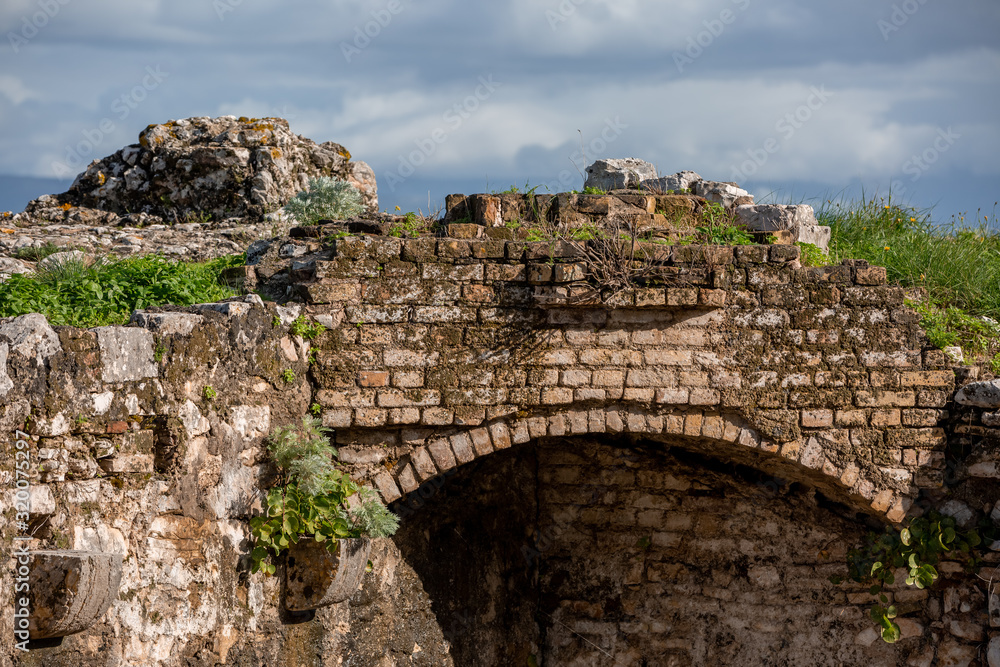 Ancient ruins of the old fortress with arched walk-through ways covered with green plants