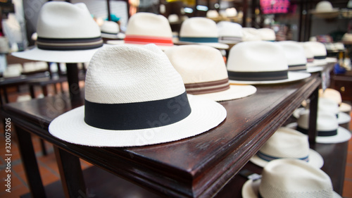 Set of several white panama hats exposed in a shop. The one in the foreground is focused, the others on the background are blurred