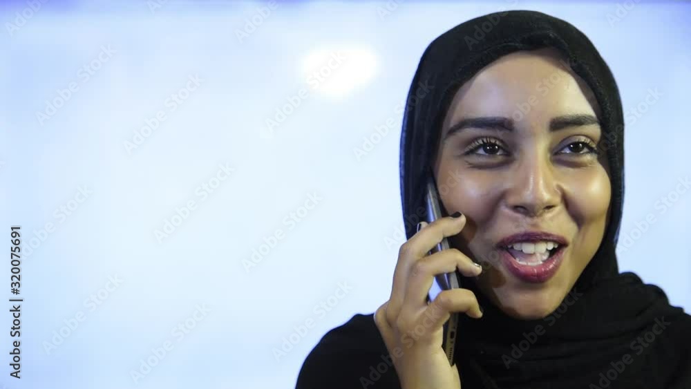 Muslim girl wearing Hijab, talking on the phone and smiling Muslim girl wearing Hijab, talking on the phone and smiling