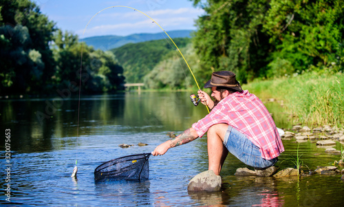 I catch it by myself. bearded man with fish on rod. hipster fishing with spoon-bait. fly fish hobby. Hipster in checkered shirt. successful fisherman in lake water. big game fishing. relax on nature